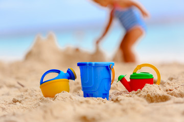 kids toys and little girl building sandcastle at beach