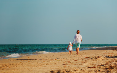 Father and little daughter walk on beach