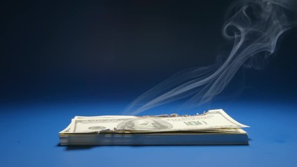 SLOW MOTION: Heap of paper money (US dollar) smoking
