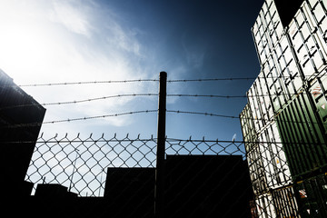 Security fence with shipping containers behind.