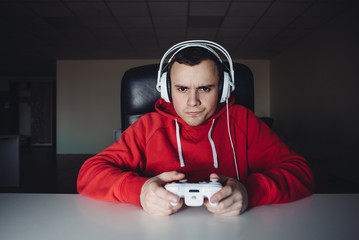 The young man home and playing games on the joystick. Gamer plays computer games using a gamepad. © bodnarphoto