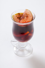 Hot mulled wine with spices, apple and orange on white background