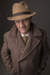 Mature man dressed as a 1940s gangster, on a dark background 