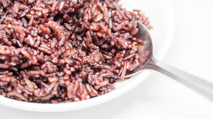 Closeup of cooked rice (RiceBerry) on white plate and spoon.
