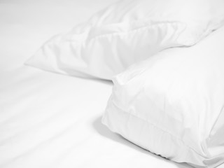 Closeup of white and bolster and blurry pillow on bed in bedroom.