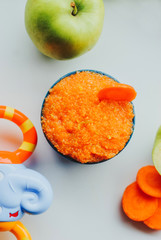 Baby food carrot puree with green apples in ceramic bowl on white background