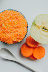 Baby food carrot puree with green apples in ceramic bowl on white background