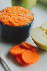 Baby food carrot puree with green apples in ceramic bowl on white background