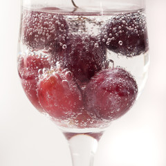 Red grapes with bubbles in a glass of soda