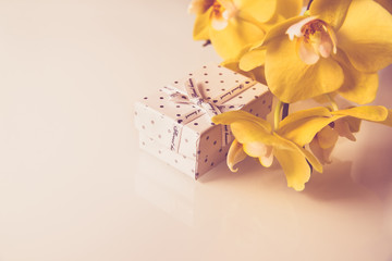 Gift box on a background of yellow orchids