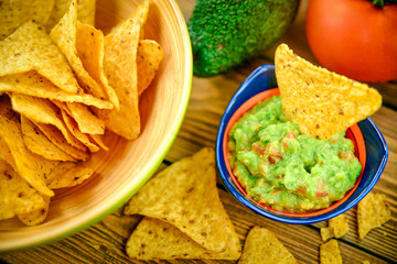 Homemade guacamole with corn chips on rustic wooden table