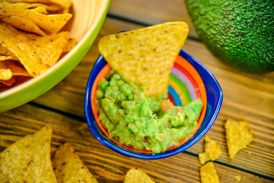 Homemade guacamole with corn chips on rustic wooden table