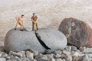 Two heavy workers grafting on a burst rock - miniature figures