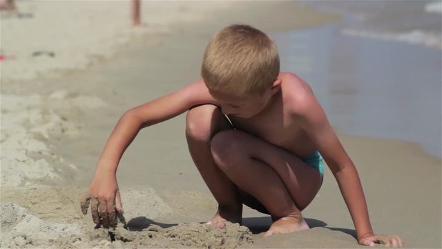 beach vacation boy/ittle boy resting on the sand by the sea on vacation