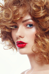 Fototapeta premium Young beautiful blue-eyed woman with curly hair and red lipstick