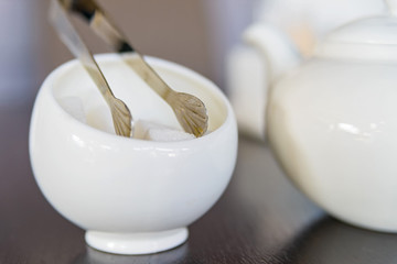 Sugar cubes in sugar bowl and sugar tongs