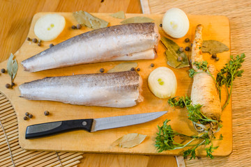 Fish fillet with onion and parsley on wooden tray background