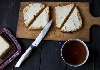 Served table for breakfast sandwiches with butter , tea on a wodden background