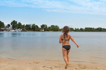Little girl runs along the beach to the water