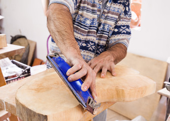 hands of a carpenter emery piece of wood in th studio