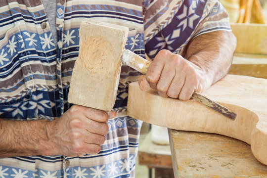 hands of carpenter processing wood with a chisel