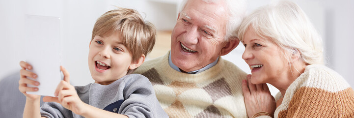 Boy showing tablet to grandparents
