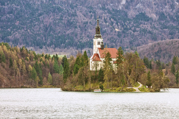 Slovenia - Bled - Lake Bled, Bled island and church of Assumption of Mary with blurred surrounding mountains covered by forest