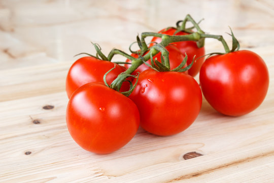 Bunch of fresh organic tomatoes on a wooden background
