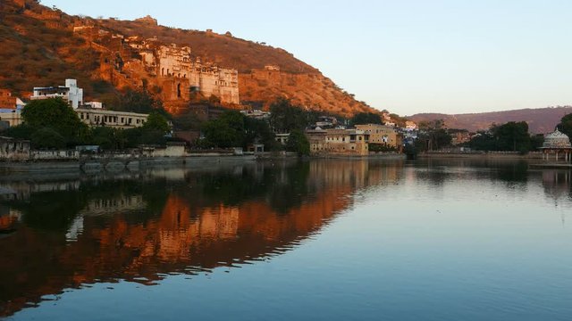 Bundi cityscape with the majestic palace and walls reflecting on water pond, travel destination in Rajasthan, India.