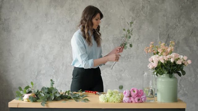 people, business, sale and floristry concept - happy smiling florist woman making bunch at flower shop, bouquet with peone and roses