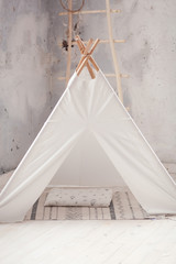 Childen's room corner with a beautifully decorated play tipi tent and a round grey carpet © oksana_bondar