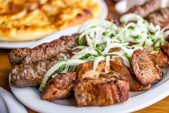 Traditional Georgian mtsvadi pork barbecue and Kebab with onion and parsley