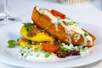 Baked fish with vegetables on the table in a composition with a glass of wine