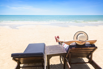 Woman relaxing on beach lounge chair or sun deck with sea view on beach, Concept of vacation beach and sea in summer holiday