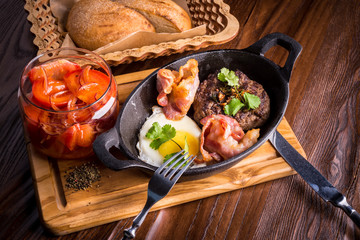 Frying pan, fried eggs, bread, steak, bacon and tomatoes