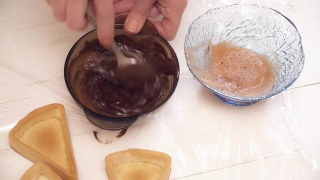Woman's hands adding the syrup to the hot chokolate in the glass bowl