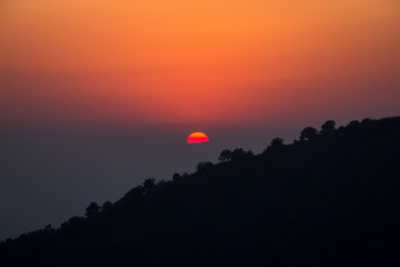 Sunset against the backdrop of a mountain with a forest
