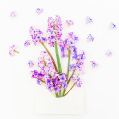 Bouquet of pink hyacinth flowers, petals and paper envelope on white background. Flat lay, top view.
