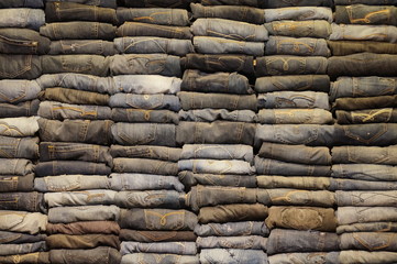 A large number of denim pants in a trendy boutique on the counter. Wall of jeans. The last collection of men's and women's clothing.