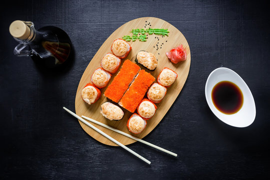 Asian food - sushi rolls, sauce, wasabi and chopsticks on a black background. Top view. Flat lay. Restaurant food.