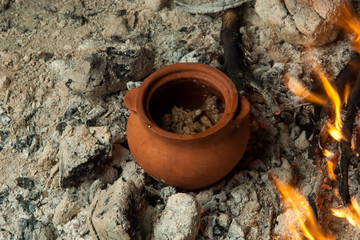 Obraz premium a dish in a clay pot is prepared on burning coals. the dish is cooked and smoked on charcoal