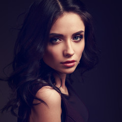 Beautiful young makeup female model with curly hairstyle looking emotional on dark shadow...