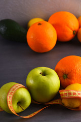 various fruits: lemon, apple, orange, avocado, grey studio wall background