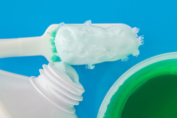 Fototapeta na wymiar Toothpaste on the toothbrush, green dental rinse, toothpaste tube on blue background, top view, macro image.
