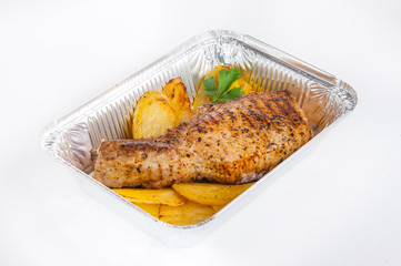Close up Healthy restaurant food delivery in foil box. Grilled meat steak and Potato Wedges. Meals take away, selective focus. Isolated on the white background.