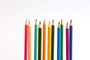 Colored pencils in a row in front of a white background