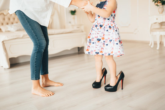 A little girl in her mother's shoes. A child dresses her mother's clothes.