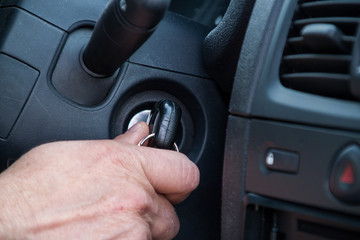 The driver is about to start the car, holds the key in his hand who is in the lock of the car