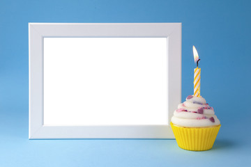 cake with candle and photo frame on blue background closeup