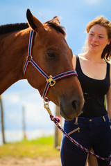 Jockey young girl petting brown horse